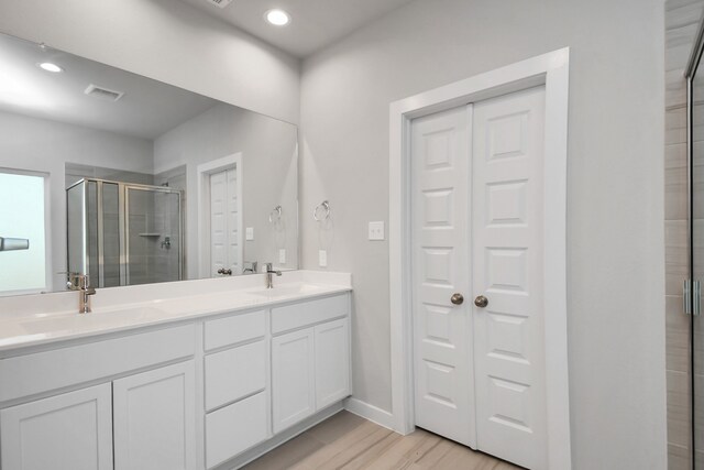 bathroom with a shower with door, wood-type flooring, and vanity