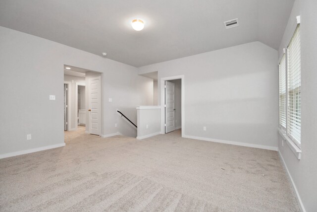 carpeted empty room with vaulted ceiling