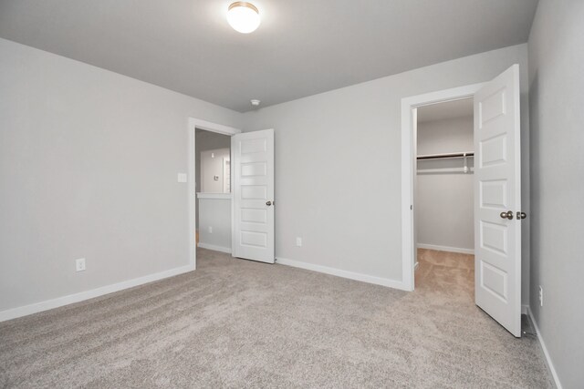 unfurnished bedroom featuring light colored carpet, a closet, and a walk in closet