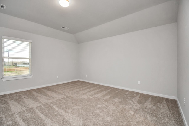 carpeted spare room featuring vaulted ceiling