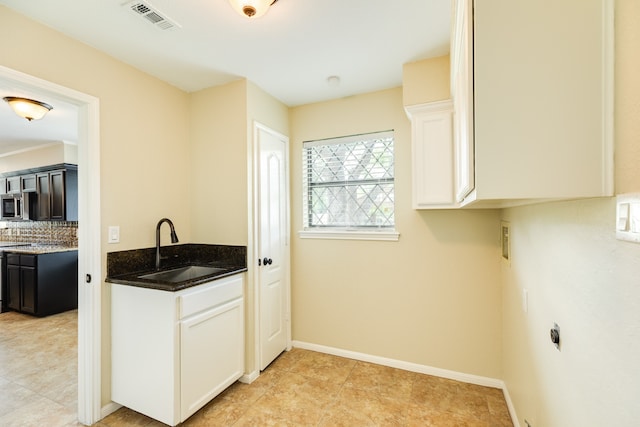 kitchen with sink, white cabinetry, decorative backsplash, and dark stone countertops