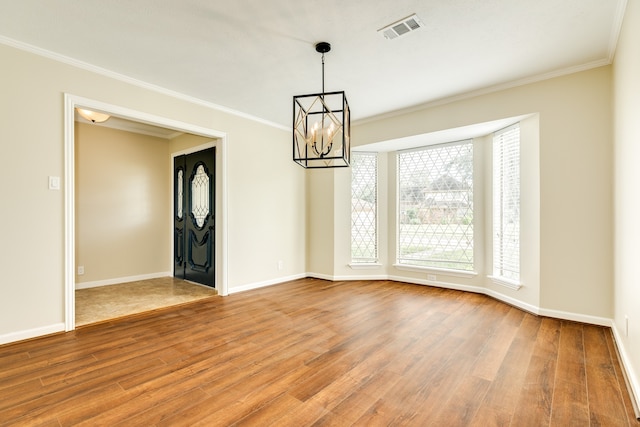 empty room with a notable chandelier, ornamental molding, and hardwood / wood-style flooring