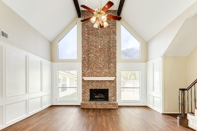 unfurnished living room featuring beam ceiling, wood-type flooring, and high vaulted ceiling