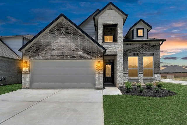 french country home with a lawn, driveway, stone siding, and an attached garage