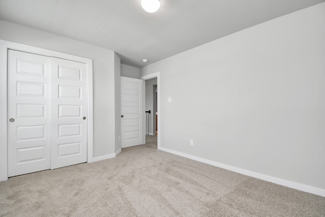 unfurnished bedroom featuring light colored carpet and a closet