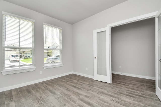 unfurnished bedroom with multiple windows, hardwood / wood-style floors, and french doors