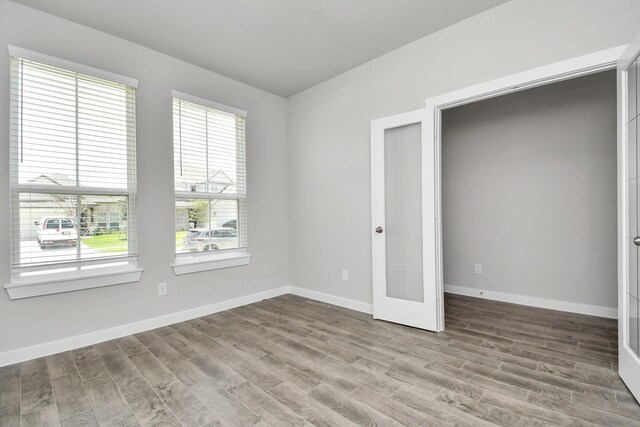 unfurnished room with baseboards, wood finished floors, and french doors