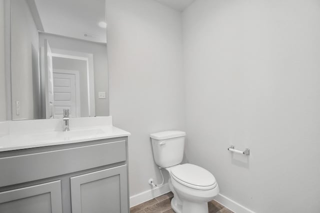 bathroom featuring vanity, wood tiled floor, toilet, visible vents, and baseboards