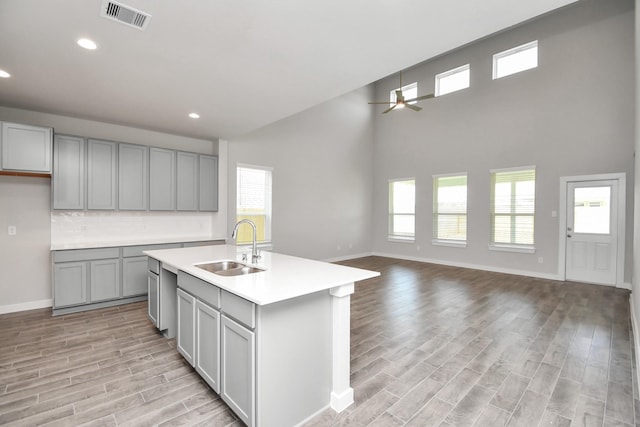 kitchen with light wood finished floors, a sink, a ceiling fan, visible vents, and gray cabinetry