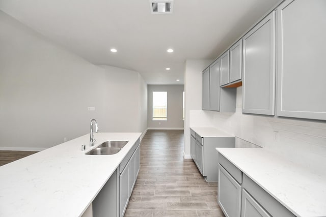 kitchen with a sink, visible vents, light wood-style flooring, and gray cabinets