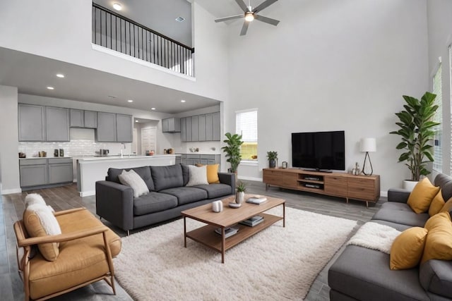 living room featuring ceiling fan, a high ceiling, and dark hardwood / wood-style flooring