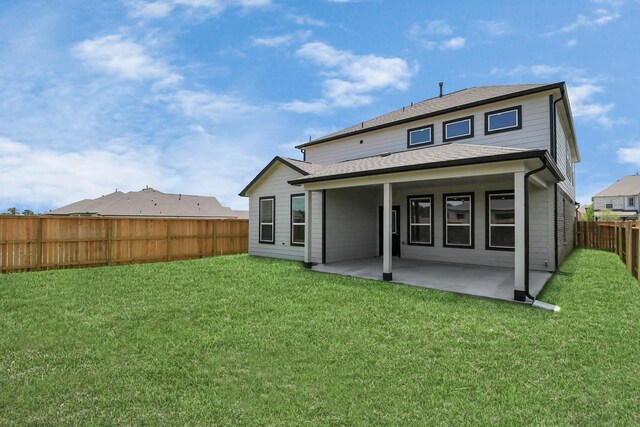 rear view of house with a lawn, roof with shingles, a fenced backyard, and a patio area