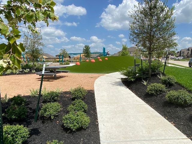 view of property's community featuring playground community and a yard
