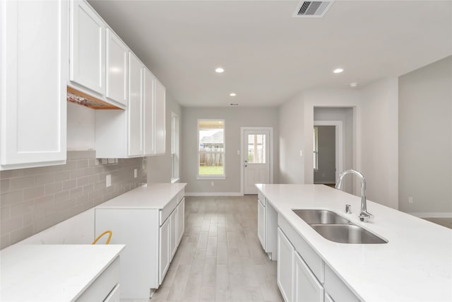 kitchen with sink, white cabinetry, light hardwood / wood-style floors, and tasteful backsplash