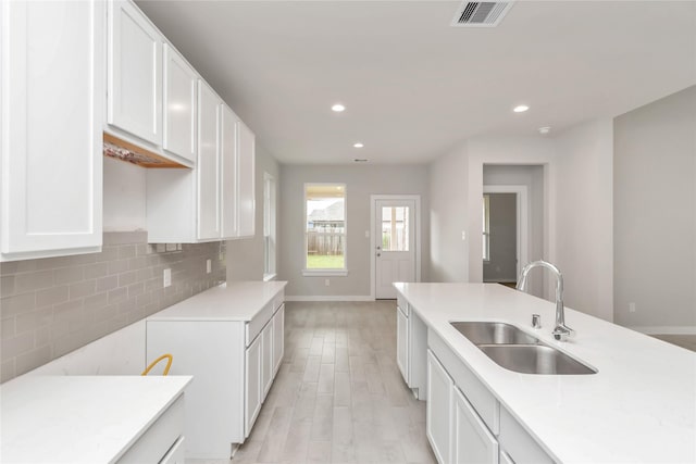 14707 Surfbird Ln, Houston, TX 77049 - kitchen with a sink, baseboards, white cabinets, light countertops, and backsplash