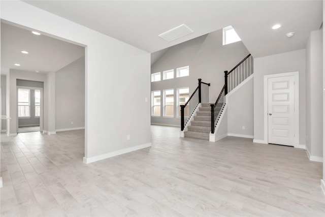 14707 Surfbird Ln, Houston, TX 77049 - unfurnished living room with baseboards, light wood-style flooring, stairs, and recessed lighting