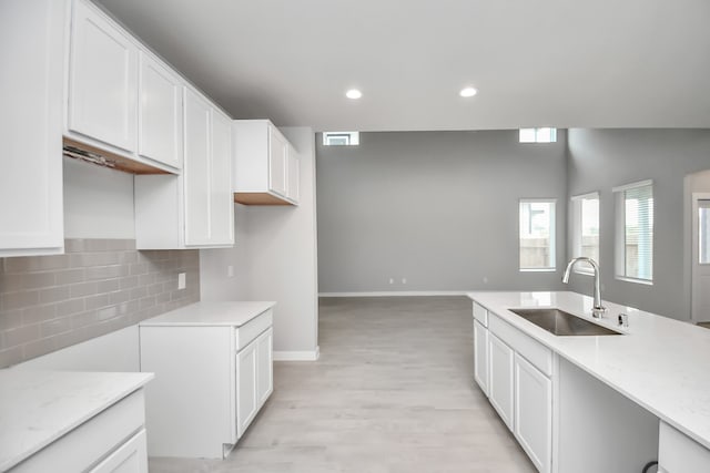 kitchen featuring sink, white cabinetry, decorative backsplash, and light hardwood / wood-style floors