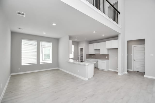 kitchen featuring sink, white cabinetry, kitchen peninsula, and light hardwood / wood-style flooring