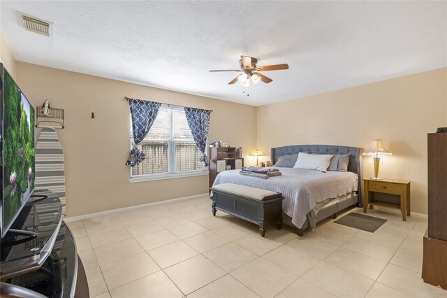 bedroom with ceiling fan, a textured ceiling, and light tile patterned flooring