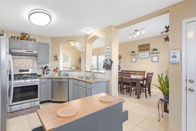 kitchen with gray cabinetry, backsplash, sink, light tile patterned flooring, and appliances with stainless steel finishes