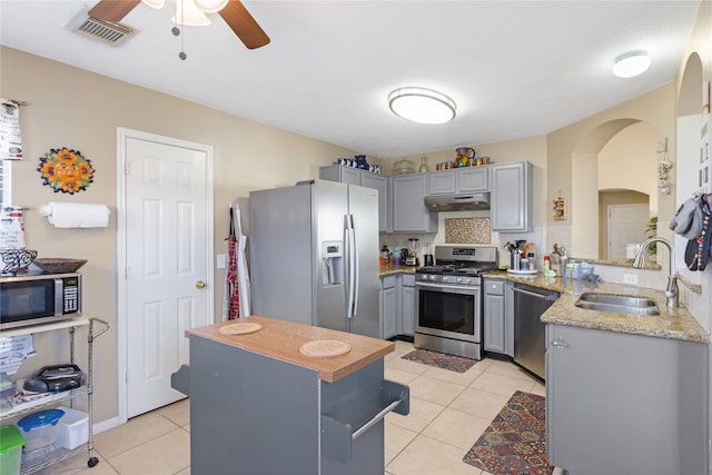 kitchen featuring gray cabinetry, sink, stainless steel appliances, decorative backsplash, and light tile patterned floors