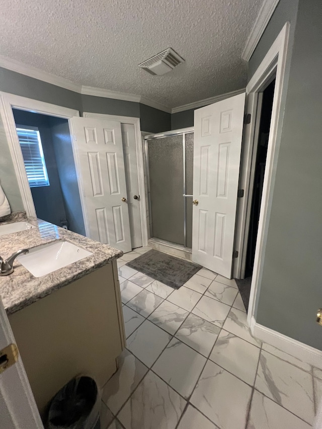 bathroom featuring a shower with door, ornamental molding, vanity, and a textured ceiling