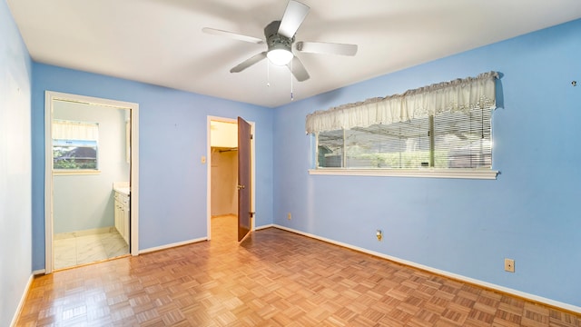 unfurnished bedroom featuring connected bathroom, ceiling fan, light parquet flooring, and multiple windows