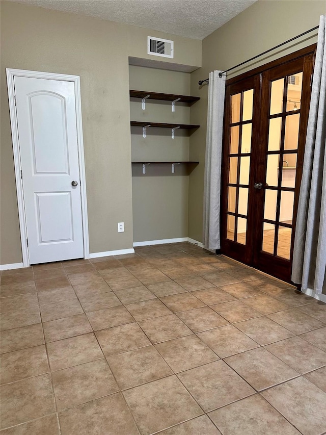 7029 N Holiday Dr, Galveston, TX 77550 - interior space with a textured ceiling, light tile patterned floors, visible vents, baseboards, and french doors