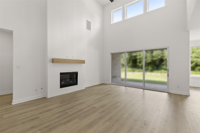 4622 Sycamore Way Rd, Fulshear, TX 77441 - unfurnished living room with a high ceiling, wood finished floors, and a large fireplace