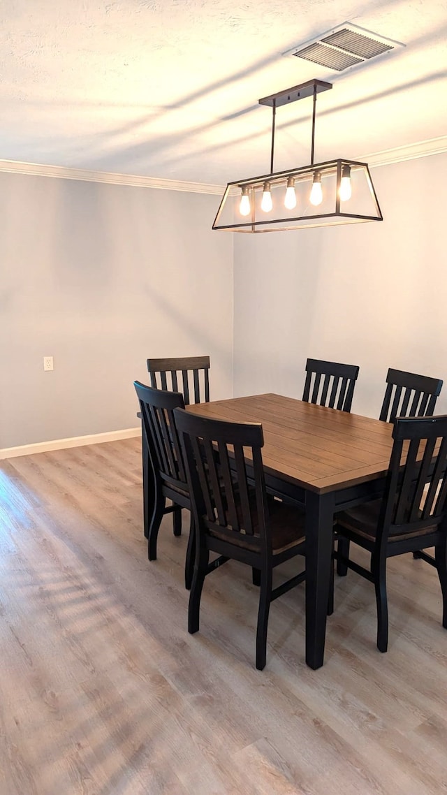 dining area with light wood-type flooring and ornamental molding