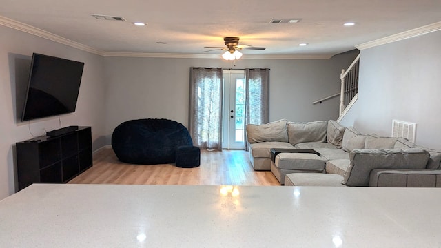 living room with crown molding, light hardwood / wood-style flooring, and ceiling fan