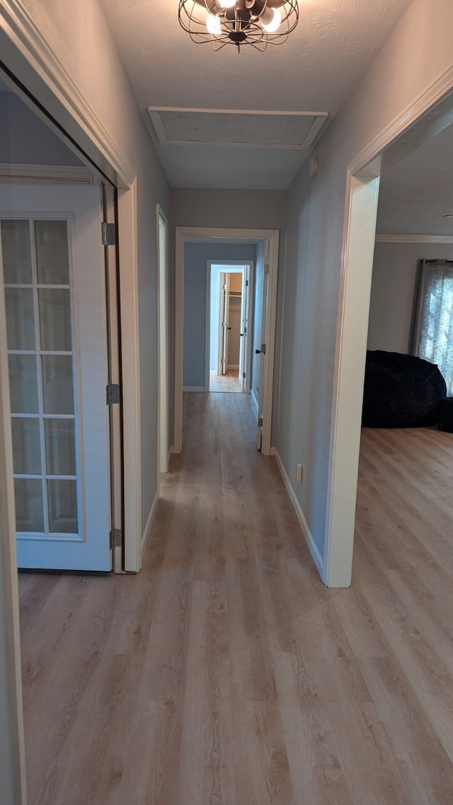 corridor with light hardwood / wood-style floors and a textured ceiling