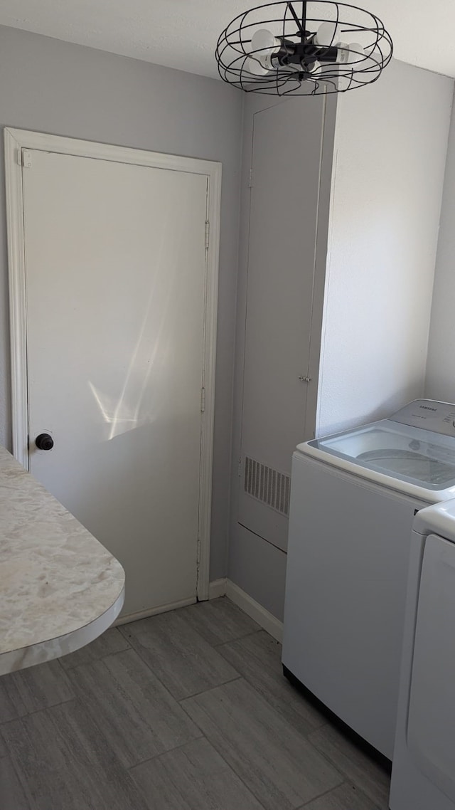 laundry room featuring washer and clothes dryer and a chandelier