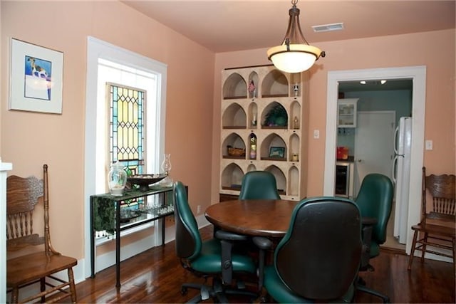 dining area featuring dark hardwood / wood-style flooring, built in features, and beverage cooler