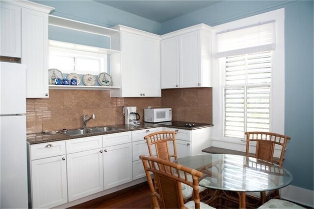 kitchen featuring dark hardwood / wood-style flooring, backsplash, white appliances, sink, and white cabinetry