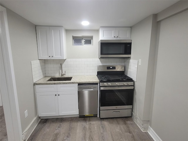 kitchen featuring sink, stainless steel appliances, light stone counters, backsplash, and white cabinets