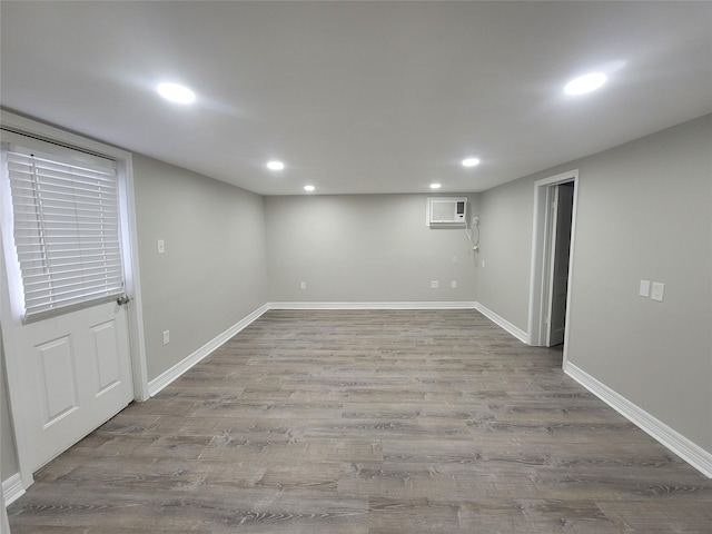 basement with a wall mounted air conditioner and light wood-type flooring