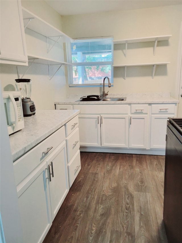 kitchen with white cabinets, sink, light stone counters, and dark hardwood / wood-style flooring