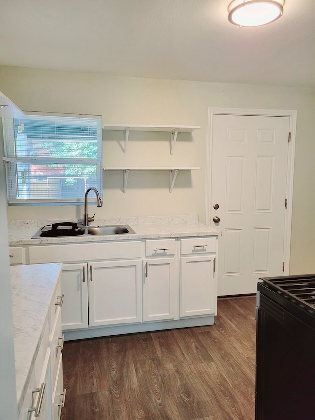 kitchen with white cabinets, dark hardwood / wood-style flooring, light stone countertops, black / electric stove, and sink