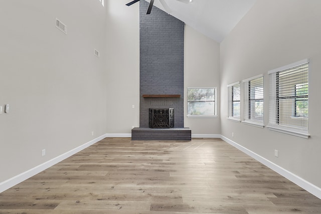 unfurnished living room with a brick fireplace, high vaulted ceiling, light hardwood / wood-style floors, and ceiling fan