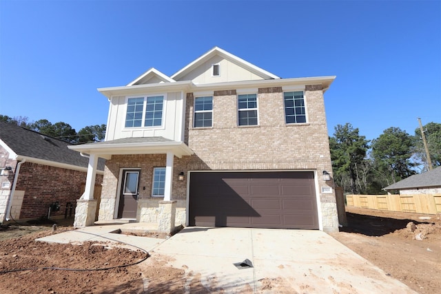 view of front facade featuring brick siding, an attached garage, board and batten siding, fence, and driveway