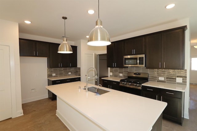 kitchen featuring a kitchen island with sink, appliances with stainless steel finishes, light countertops, and a sink