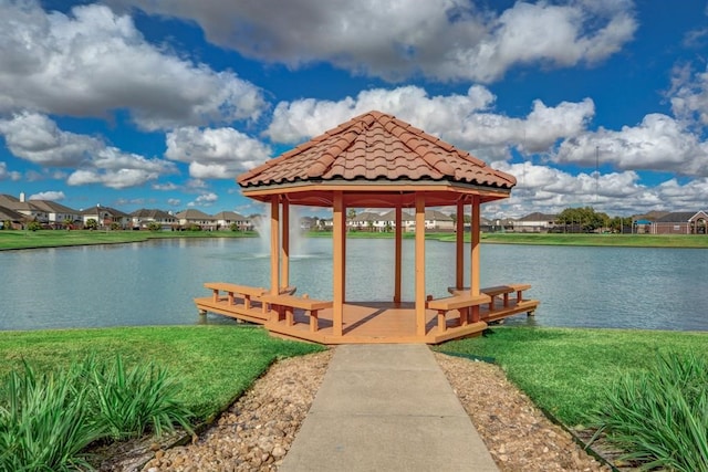 view of dock with a gazebo, a water view, and a lawn