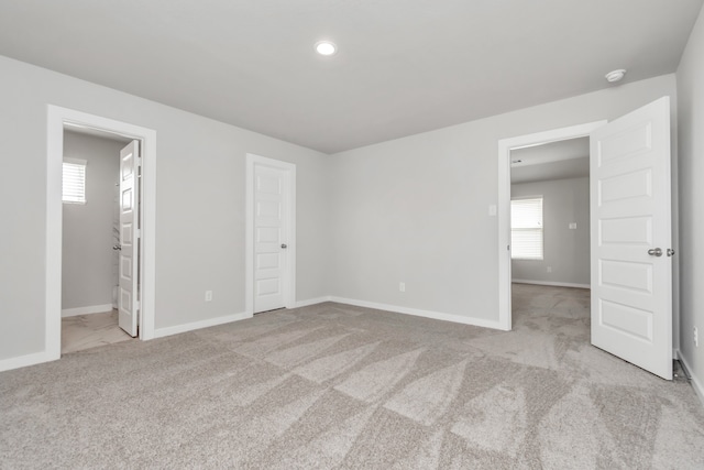 unfurnished bedroom with ensuite bathroom and light colored carpet