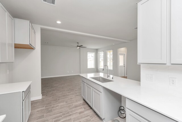 kitchen with light hardwood / wood-style floors, white cabinetry, sink, and ceiling fan