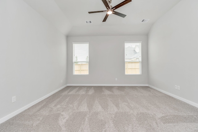 empty room featuring light carpet, a healthy amount of sunlight, lofted ceiling, and ceiling fan