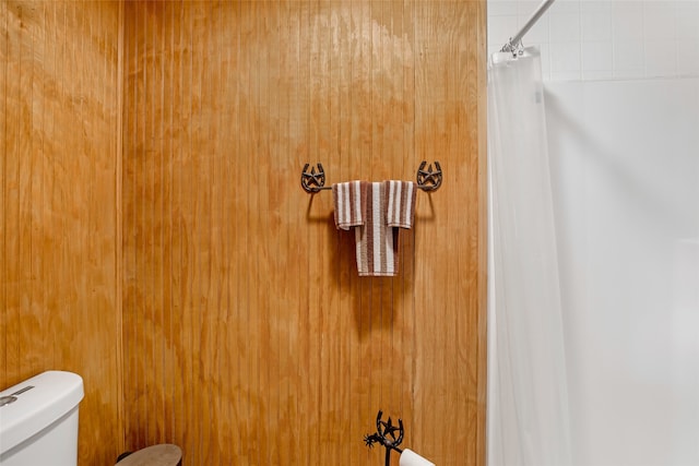 bathroom with toilet, wood walls, and curtained shower