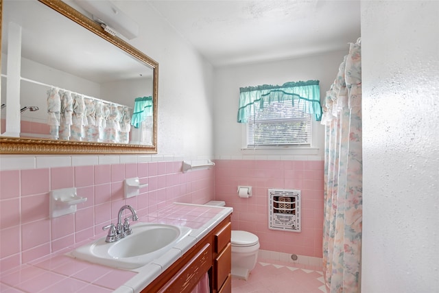 bathroom with toilet, tile walls, heating unit, vanity, and tile patterned flooring