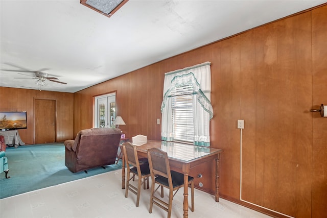 dining room with ceiling fan and wood walls