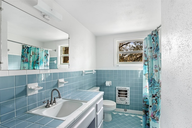 bathroom with toilet, tile patterned flooring, vanity, heating unit, and tile walls